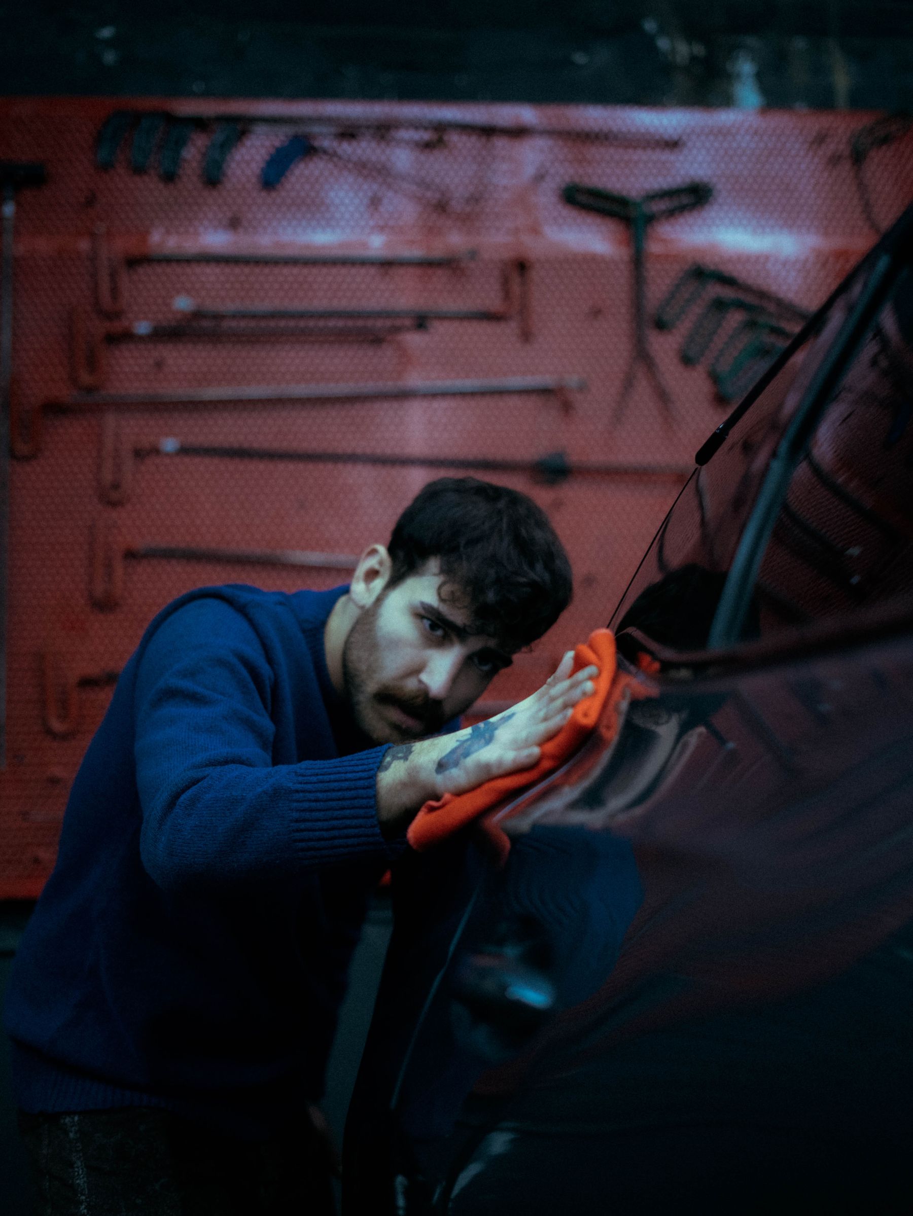 Technician polishing a car in a dark workshop